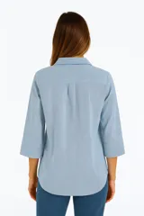 Blusa celeste con rayas verticales blancas, cuello camisero, escote en V y mangas 3/4.