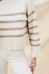 Suéter de punto color crema con rayas horizontales marrones, cuello alto y mangas largas.