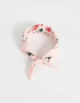 Pañuelo de tela color rosa claro con estampado de flores y letras en negro, rojo y verde.