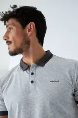 Remera tipo polo color ocre, de corte clásico, con cuello y mangas con terminaciones a contratono en azul marino y blanco.