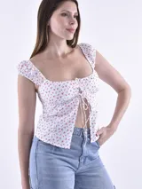 Blusa blanca con estampado de cerezas, escote cuadrado, mangas cortas abullonadas y cierre frontal con lazos.