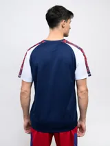 Remera de entrenamiento azul marino con detalles en blanco y rojo en los hombros y mangas. Incluye el logo de Umbro y el escudo del Club Nacional de Football en el pecho.