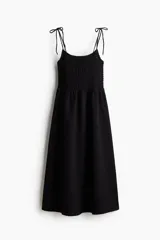 Vestido midi negro con cuerpo entallado fruncido, escote redondo y breteles spaghetti. Costura fruncida en la cintura y pollera con leve vuelo.
