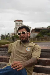 Remera color beige de manga corta con cuello redondo y estampado de un sol con montañas en el pecho.