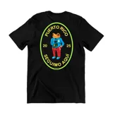 Remera negra de algodón con estampado en la espalda de un sapo coquí vestido con ropa y una cámara, dentro de un óvalo amarillo con el texto "Puerto Rico", "Seguimos Aquí" y los números "20" y "25".