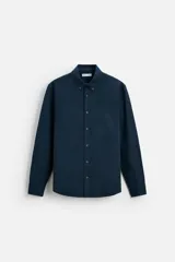 Camisa azul marino de corte regular fit, confeccionada en tejido de algodón Oxford. Tiene cuello abotonado, manga larga con puños abotonados, bolsillo de parche en el pecho y cierre frontal con botones.