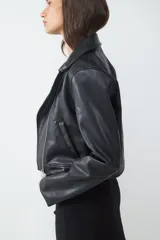 Campera biker negra de efecto cuero, con cierre delantero asimétrico, bolsillos laterales con cierre y cuello con solapa adornado con tachas.