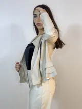 Chaqueta beige de cuero sintético con cierre lateral y volados en la espalda baja.