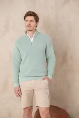 Sweater de punto color verde agua, con cuello alto y medio cierre. El tejido es de algodón pigmentado con efecto gastado y lavado.