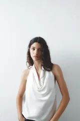 Top negro de satén con cuello halter drapeado ajustable con lazada en el cuello y espalda descubierta con lazada.