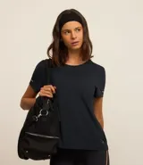 Remera deportiva negra texturizada, de cuello redondo y manga corta, con detalle reflectante en la manga y pliegue en la espalda.