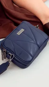 Bandolera pequeña de símil cuero color marrón, con diseño acolchado en forma de rombos. Posee doble cierre metálico en el compartimento principal, bolsillo trasero y correa ajustable de tela tipo galón.