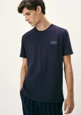 Camiseta blanca de algodón con cuello redondo y mangas cortas. Estampa rectangular con borde negro que contiene la frase "NATURAL ATMOSPHERE" en letras mayúsculas y una imagen de montañas y mar.