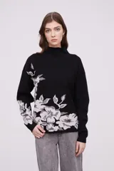 Sweater de tejido suave con estampado floral en tonos beige y blanco, con cuello alto y mangas largas.