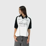 Polo oversize blanco y negro con cuello clásico, mangas cortas y estampado con el logo de la marca en el frente.