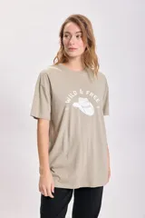 Remera color arena de corte oversize con estampa de un sombrero de cowboy y la frase "Wild & Free" en blanco.