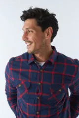 Sobrecamisa de algodón para hombre con interior de corderito, estampado a cuadros en tonos negro, blanco y azul. Tiene cierre de botones, bolsillos tipo cartera y logo en goma. El modelo usa talle M.