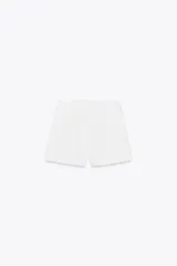 Bermuda negra de tiro alto con bolsillos delanteros de vivo y cierre lateral con cremallera oculta en costura.