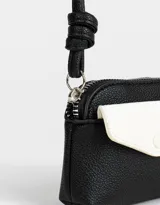 Monedero pequeño de cuerina bicolor, negro y blanco, con bolsillo frontal con broche y cierre superior con tirador de cordón. Incluye correa fina para colgar.