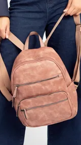 Mochila color rosa de símil cuero con bolsillos frontales con cierre. Tiene asa de mano rígida y correas regulables.