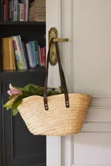 Bolso capazo de rafia natural con asas de cuero marrón.