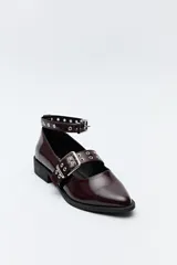Zapato tipo zueco negro charol con punta fina, doble tira con hebillas metálicas y pulsera al tobillo con tachas.