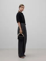 Bolso de mano negro de poliéster con asa rígida dorada con forma de cubos.
