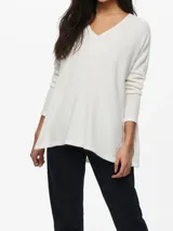 Sweater de tejido de punto color blanco roto, con escote en V y mangas largas. Presenta un calce ajustado y suave.