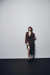Vestido largo marrón con lunares negros, cuello halter ajustable, escote drapeado, espalda descubierta con tira ajustable y cierre lateral con cremallera oculta.
