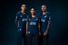 Camiseta de fútbol Umbro del Club Nacional de Football, modelo Alternativa. Diseño azul con detalles en blanco y rojo en cuello y mangas. Incluye logo de Umbro, escudo del club y sponsor Antel en el frente.