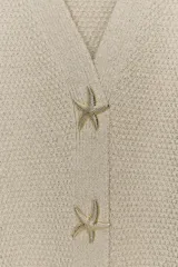 Chaqueta amarilla de punto con escote de pico y manga corta. Cierre frontal con botones en forma de estrella.
