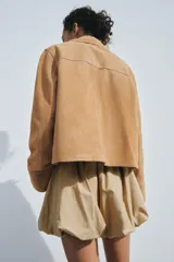 Chaqueta de mujer realizada en piel de ante color beige. Tiene cuello solapa, manga larga, bolsillos de plastrón en delantero y cierre frontal con botones.