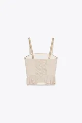 Top corto de escote recto y tirantes finos, con estampado de cuadros vichy en tonos beige y blanco. Presenta tejido elástico tipo nido de abeja en la espalda, detalle de botones forrados en el delantero y bajo con volantes. Cierre con cremallera lateral oculta en la costura.