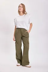 Pantalón cargo color verde oliva, de corte ancho y tiro alto, con bolsillos laterales y cierre frontal con cremallera y botón.