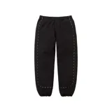 Pantalón de jogging negro con cintura elástica y cordón ajustable. Presenta detalles de ribetes blancos con texto a lo largo de las costuras laterales y en los tobillos.