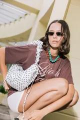 Bolso tipo cartera de nylon con diseño plisado y estampado abstracto en tonos claros.