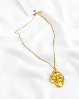 Collar de acero con dije en baño de oro en forma orgánica, con diseño texturizado.