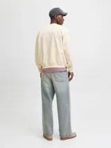 Buzo de manga larga color blanco antiguo (off-white) con cuello redondo y fit holgado. Presenta un estampado frontal con texto que incluye "ORIGINALS STUDIO", "URBAN AESTHETICS" y el número "90" en tonos rosados y dorados.