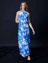 Vestido largo de gasa con estampado floral en tonos celeste y blanco. Tiene escote halter, cintura elastizada con lazo de ajuste, abertura en la espalda con botones y forro interno.