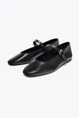 Zapato plano tipo bailarina en piel color negro, con tira sobre el empeine y hebilla metálica ajustable.