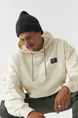 Canguro color crema con capucha ajustable, lettering estampado en el frente, logo en grifa de goma y puños.