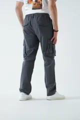 Pantalón cargo color beige, con cintura elástica ajustable con cordón, bolsillos laterales con cierre y bolsillos cargo con solapa.
