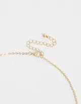 Cadena corta dorada con dije de cruz con strass.
