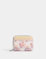 Billetera de cuerina color blanco con estampado de flores en tonos lila, naranja y amarillo. Tiene cierre superior, compartimentos para tarjetas y billetes, y un bolsillo interno con cierre.