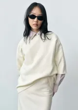Jersey color crema de punto fino, con cuello redondo, manga corta y diseño oversize.