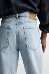 Pantalón de jean celeste de corte recto, con cinco bolsillos, efecto lavado y cierre frontal con botones.