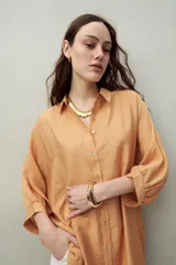 Camisa celeste de calce relajado con cuello clásico, mangas tres cuartos amplias y botones nacarados.