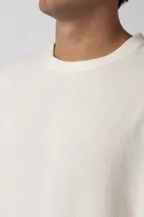 Remera color crudo de lino con textura entramada, calce cómodo y mangas cortas.