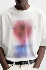 Camiseta blanca de corte relaxed fit, cuello redondo y manga corta. Estampado combinado a contraste en el delantero con imagen borrosa de flor y texto en azul.