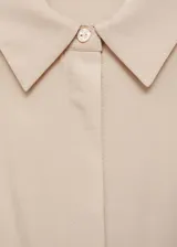 Vestido camisero midi color beige, sin mangas, con cuello camisero, cinturón negro y aberturas laterales.